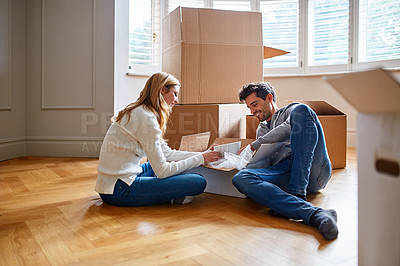 Buy stock photo Shot of a happy young couple unpacking boxes in their new house