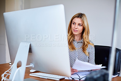 Buy stock photo Shot of a young woman sitting at a desk in her home office reading documents and working on a computer