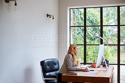 Buy stock photo Shot of a young woman working on a computer while sitting at a desk in her home office