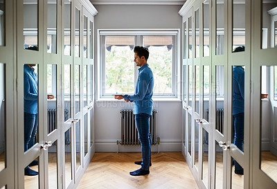 Buy stock photo Shot of a man getting dressed in a long walk in closet full of mirrors