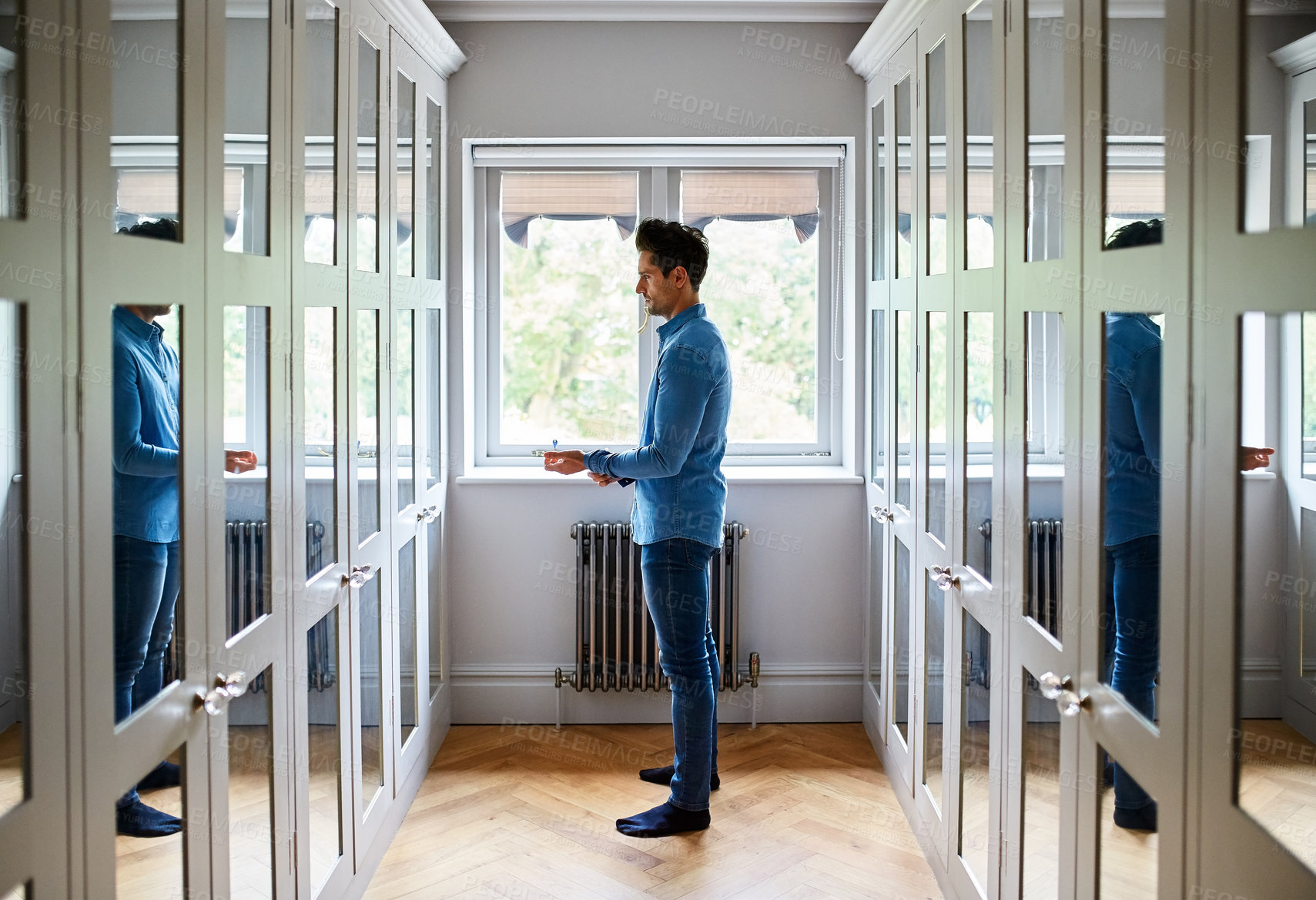 Buy stock photo Man, mirror and dressing with reflection in hallway or closet for fashion or preparation. Male person, shirt and getting ready in home corridor with long wardrobe for change, styling or grooming