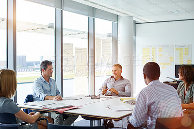 Buy stock photo Shot of colleagues having a meeting around a boardroom table in an office