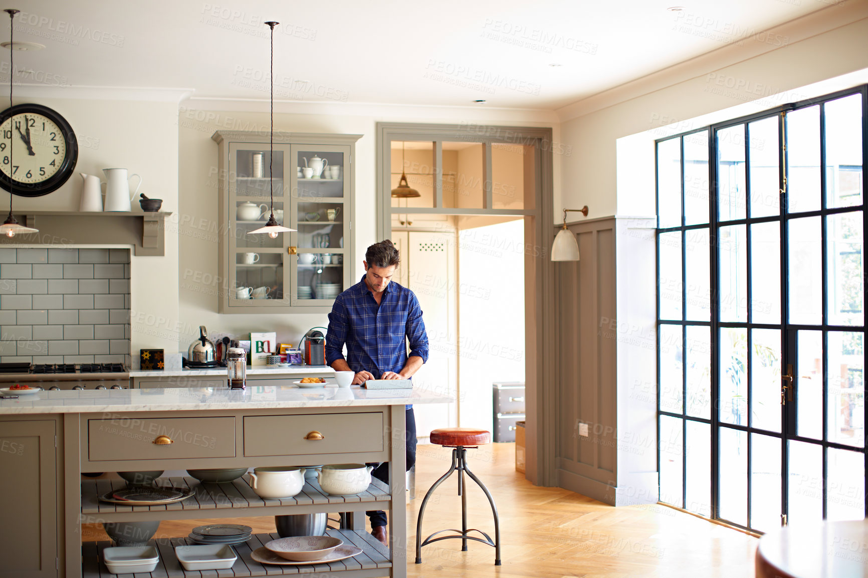 Buy stock photo Man, reading and coffee in kitchen with tablet, social media and browsing for morning news. Male person, relax and breakfast in home with digital, download ebook and internet search for weekend break