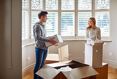 Buy stock photo Shot of a happy young couple unpacking boxes in their new house