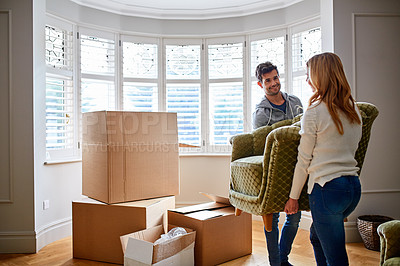 Buy stock photo Shot of a happy young couple carrying a chair in their new house