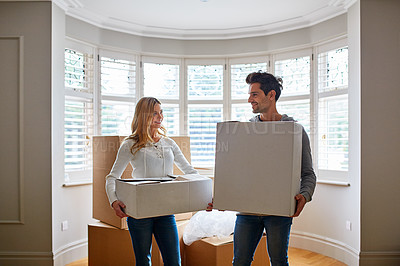 Buy stock photo Shot of a happy young couple carrying boxes in their new house