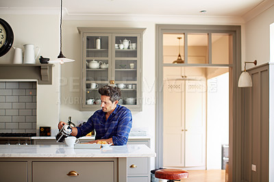 Buy stock photo Shot of a young man pouring coffee while having breakfast at home