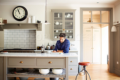 Buy stock photo Shot of a young man using a digital tablet while having breakfast at home
