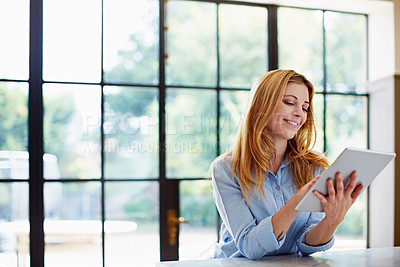 Buy stock photo Shot of a young woman using a digital tablet at home