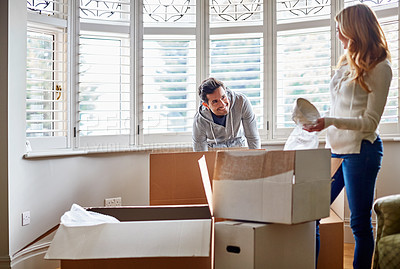 Buy stock photo Shot of a happy young couple unpacking boxes in their new house