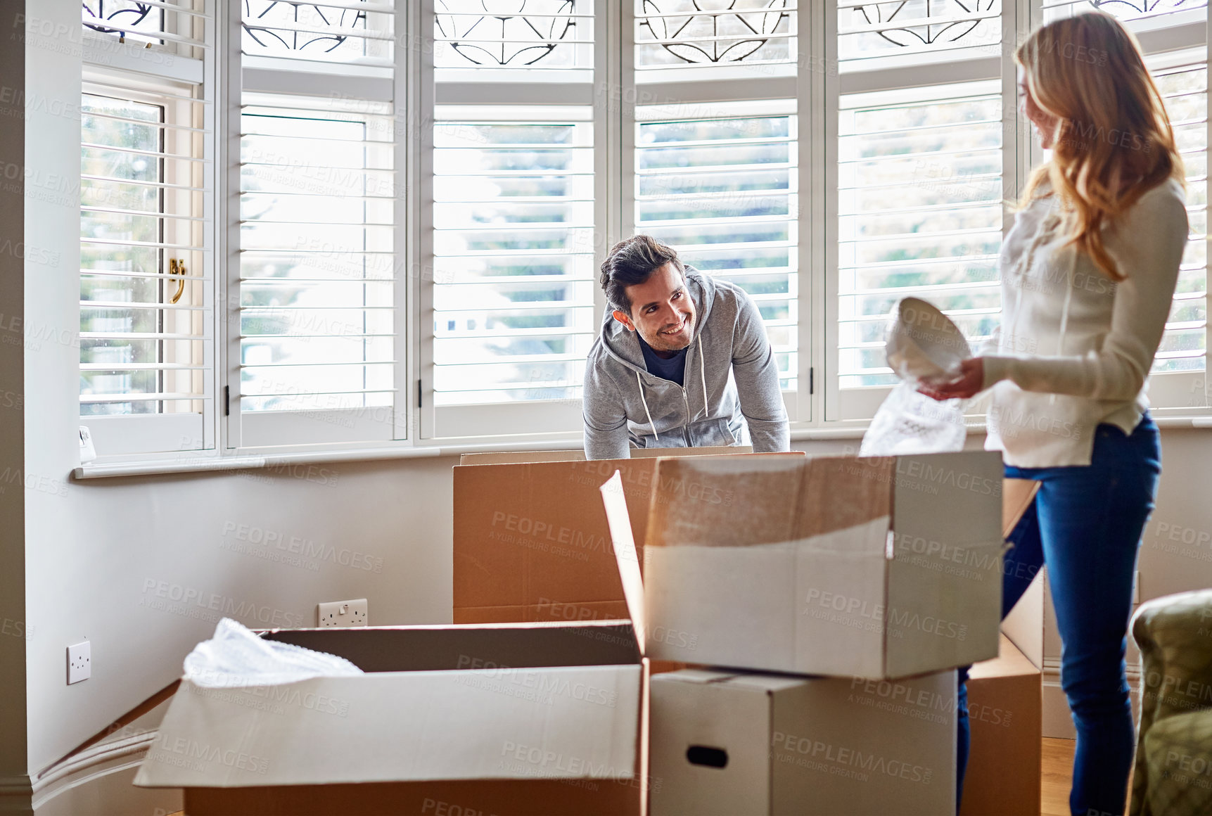 Buy stock photo Shot of a happy young couple unpacking boxes in their new house
