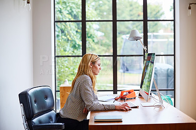 Buy stock photo Shot of a young woman using a computer while working from home