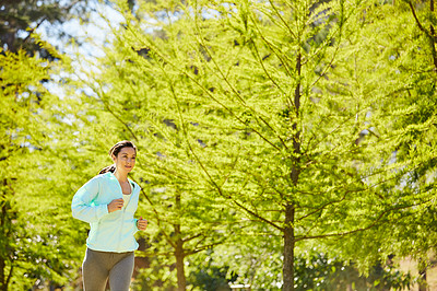 Buy stock photo Cropped shot of an attractive and athletic young sportswoman out for a jog in the park
