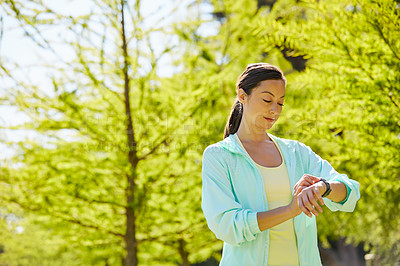 Buy stock photo Cropped shot of an attractive and athletic young sportswoman checking her watch while out for a jog in the park