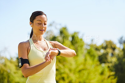 Buy stock photo Cropped shot of an attractive and athletic young sportswoman checking her watch while out for a jog in the park