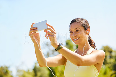 Buy stock photo Cropped shot of an attractive and athletic young sportswoman taking selfies while out for a jog in the park