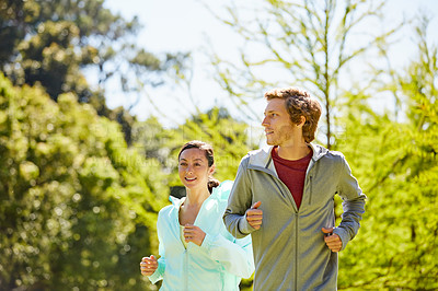 Buy stock photo Cropped shot of an affectionate and athletic young couple out for a jog in the park