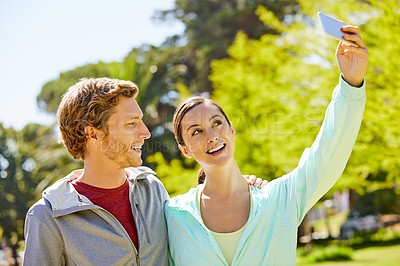 Buy stock photo Cropped shot of an affectionate and athletic young couple taking selfies while out for a jog in the park