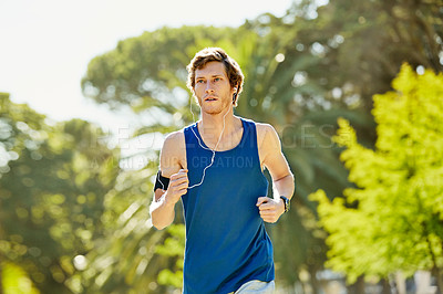 Buy stock photo Cropped shot of a handsome and athletic young sportsman listening to music while out for a jog in the park