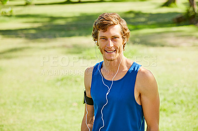 Buy stock photo Cropped portrait of a handsome and athletic young sportsman listening to music while out for a jog in the park