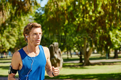 Buy stock photo Cropped shot of a handsome and athletic young sportsman out for a jog in the park