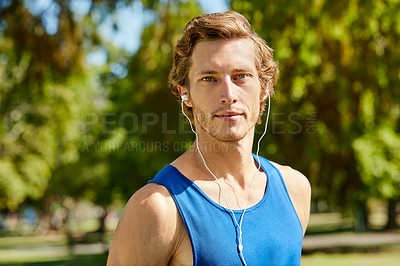 Buy stock photo Cropped portrait of a handsome and athletic young sportsman listening to music while out for a jog in the park