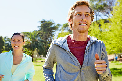 Buy stock photo Cropped shot of an affectionate and athletic young couple out for a jog in the park