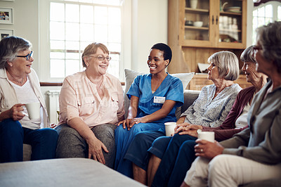 Buy stock photo Cropped shot of an attractive young nurse sitting with her senior patients in the living room of a nursing home