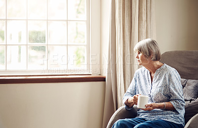 Buy stock photo Shot of a senior woman having coffee and looking thoughtfully out of a window