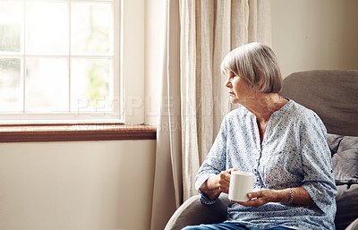 Buy stock photo Shot of a senior woman having coffee and looking thoughtfully out of a window