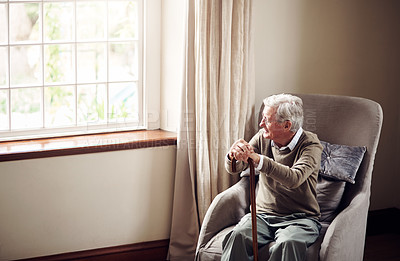 Buy stock photo Shot of a senior man looking thoughtfully out of a window at home
