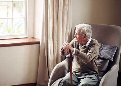 Buy stock photo Shot of a senior man looking thoughtfully out of a window at home