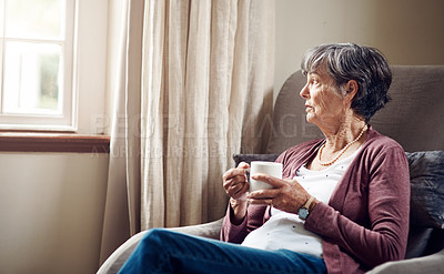 Buy stock photo Shot of a senior woman having coffee and looking thoughtfully out of a window