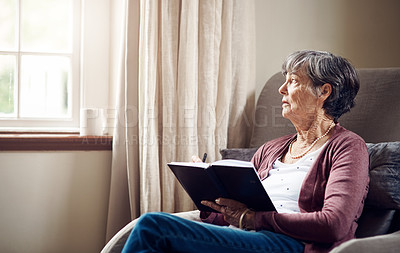 Buy stock photo Shot of a senior woman writing in a notebook at home