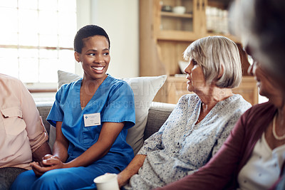 Buy stock photo Cropped shot of an attractive young nurse sitting with her senior patients in the living room of a nursing home