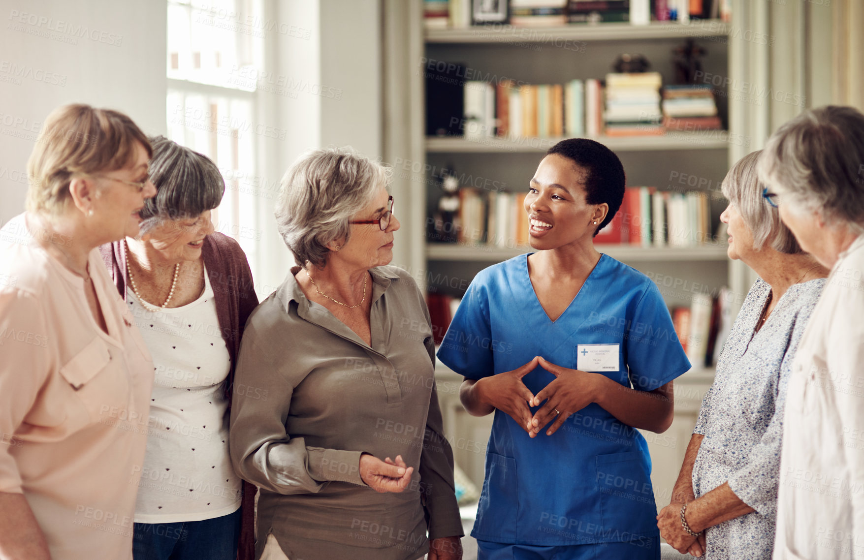Buy stock photo Cropped shot of an attractive young nurse standing with her senior patients in the living room of a nursing home