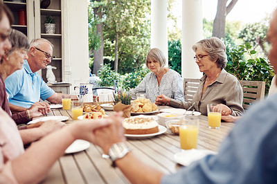 Buy stock photo Cropped shot of a group of senior citizens sitting together and holding hands to pray before enjoying their tea party