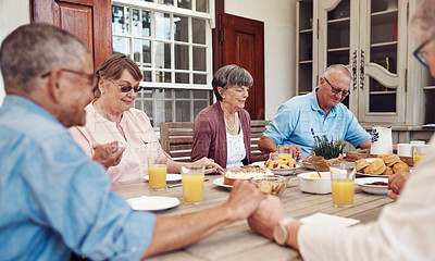 Buy stock photo Cropped shot of a group of senior citizens sitting together and holding hands to pray before enjoying their tea party