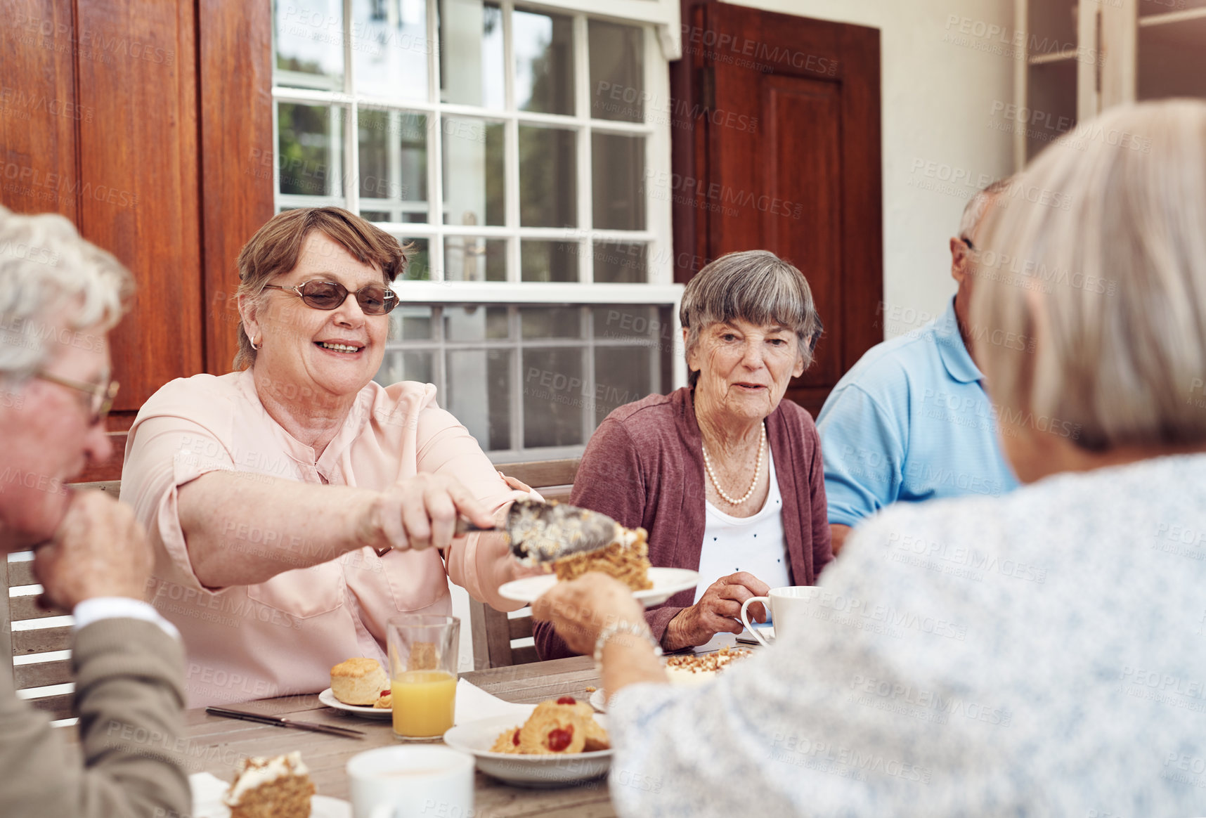Buy stock photo Cropped shot of a happy senior woman serving carrot cake to her friend during a tea party outdoors
