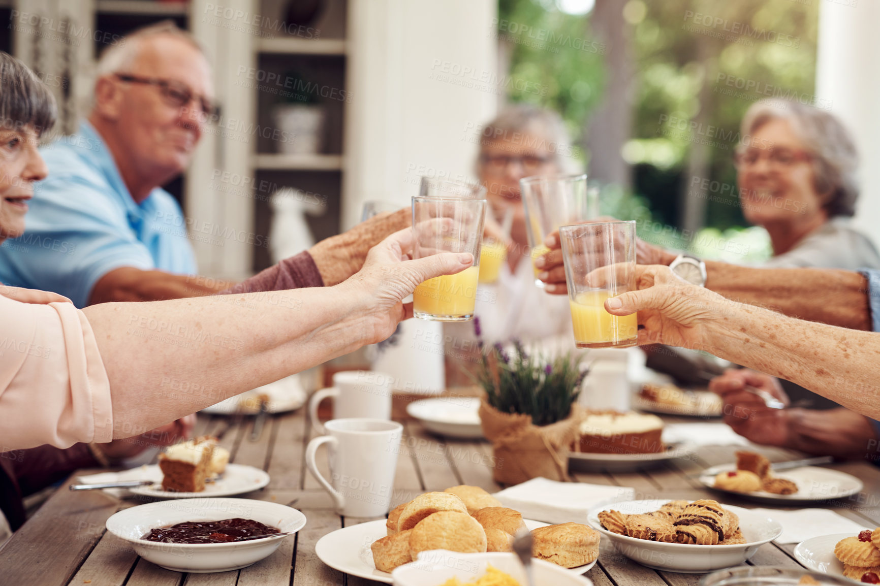 Buy stock photo Cropped shot of a group of seniors sitting together and raising their fruit juice glasses for a toast