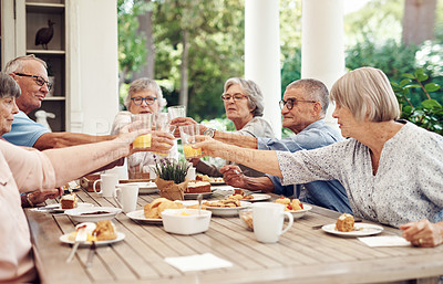 Buy stock photo Cropped shot of a group of seniors sitting together and raising their fruit juice glasses for a toast