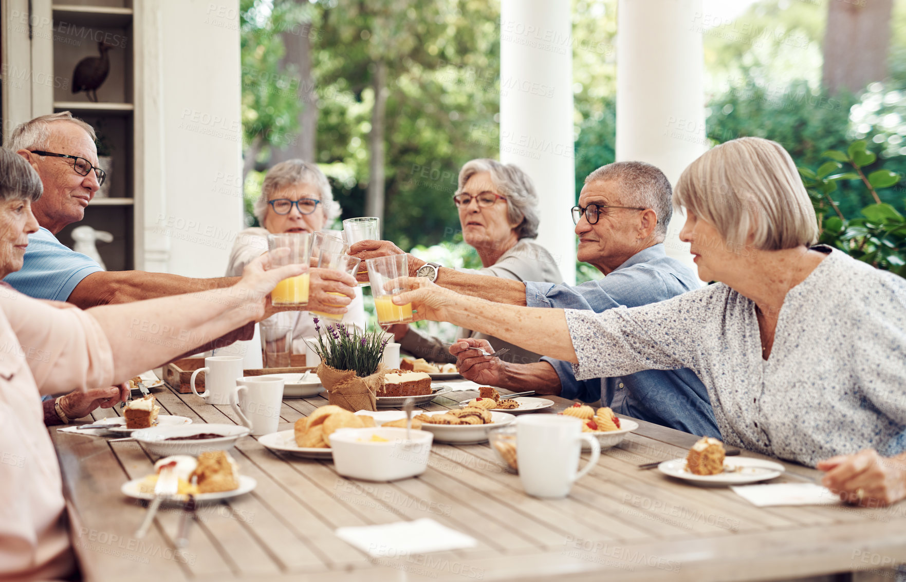 Buy stock photo Cropped shot of a group of seniors sitting together and raising their fruit juice glasses for a toast