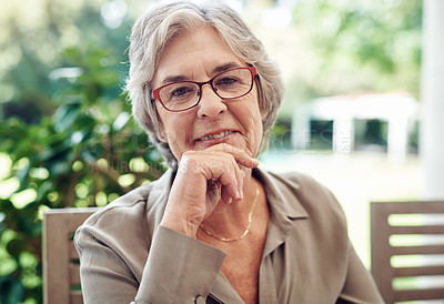 Buy stock photo Cropped portrait of a happy senior woman sitting with her hand on her chin during a tea party outdoors