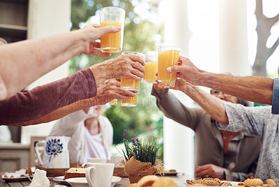 Buy stock photo Cropped shot of a group of seniors sitting together and raising their fruit juice glasses for a toast