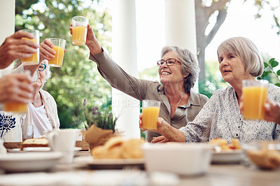 Buy stock photo Cropped shot of a group of seniors sitting together and raising their fruit juice glasses for a toast