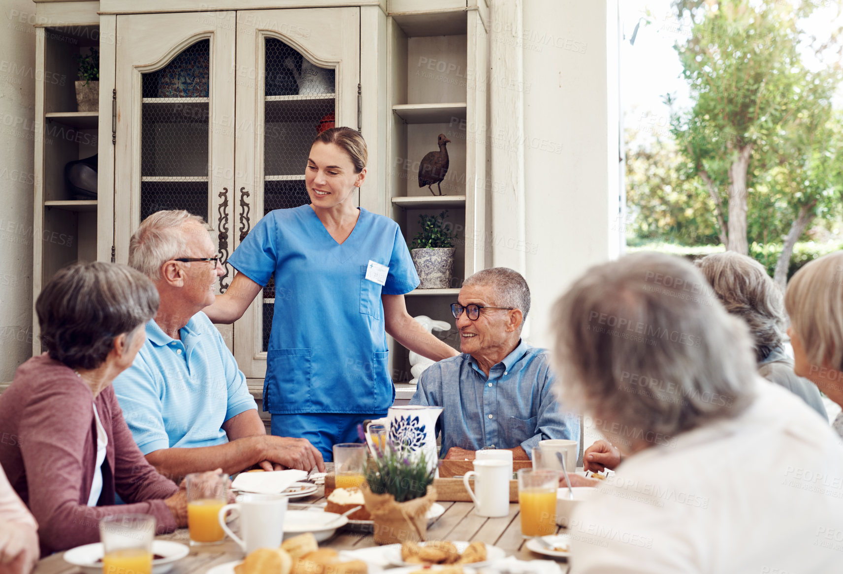 Buy stock photo Cropped shot of an attractive young nurse bonding with her senior patients during a tea party