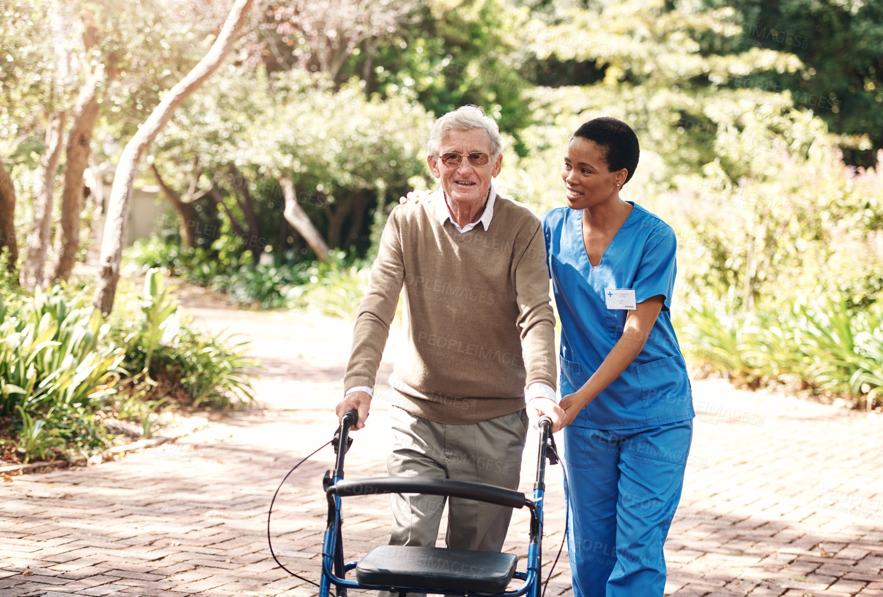 Buy stock photo Cropped portrait of an attractive young nurse helping her senior patient walk with his walker during a day outdoors