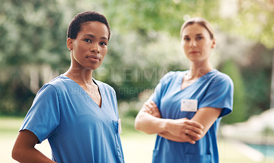 Buy stock photo Portrait of two confident young nurses standing outside in the garden of a retirement home
