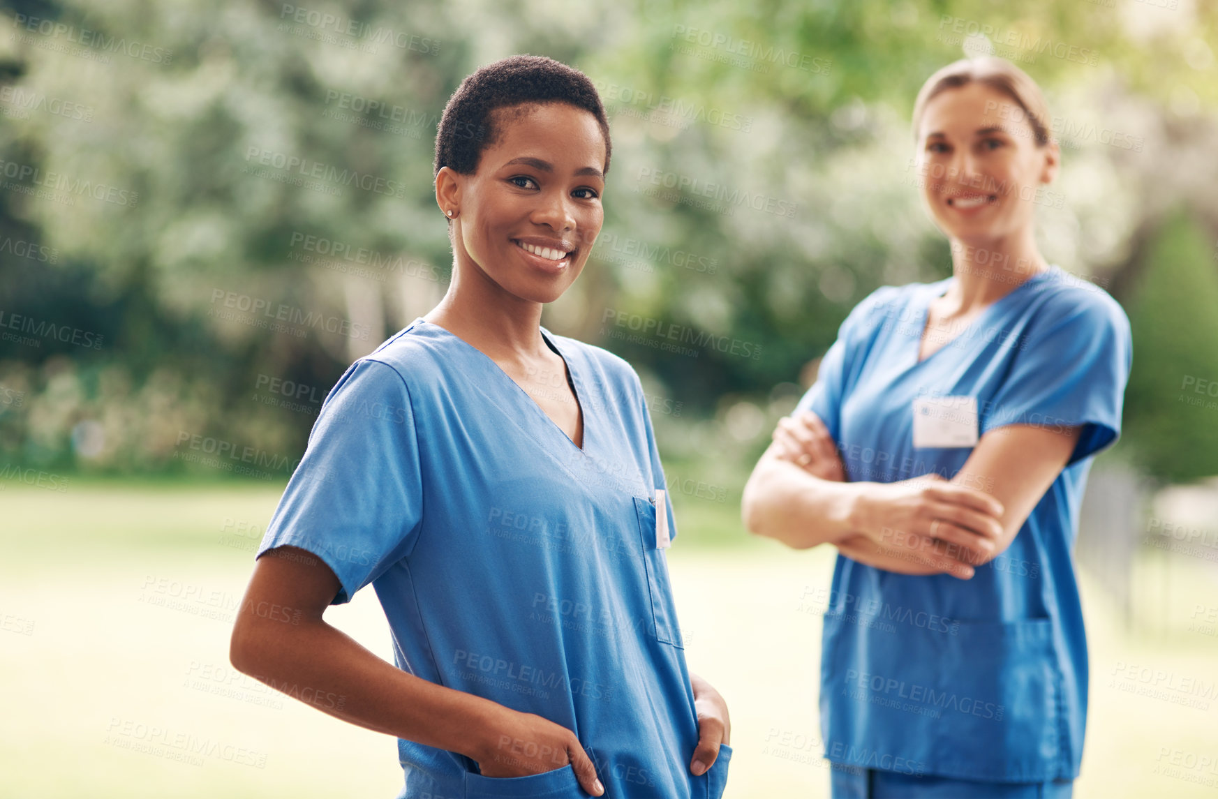 Buy stock photo Portrait of two confident young nurses standing outside in the garden of a retirement home
