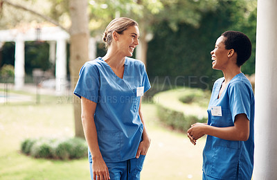 Buy stock photo Shot of two young nurses talking outside in the garden of a retirement home